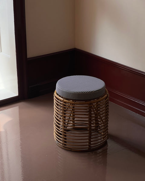 Vintage rattan stool with striped cushion